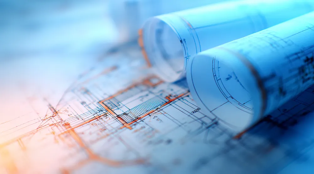Rolled blueprints on top of construction drawings representing careful planning to reduce stress during remodeling