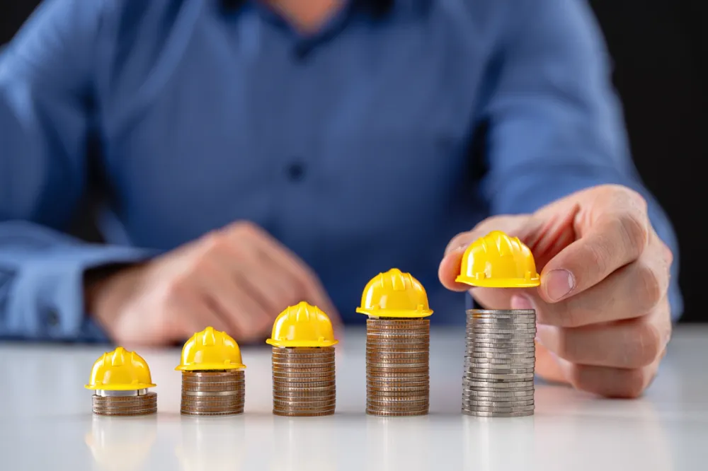 Stacks of coins with small hard hats representing saving money through pre-construction planning